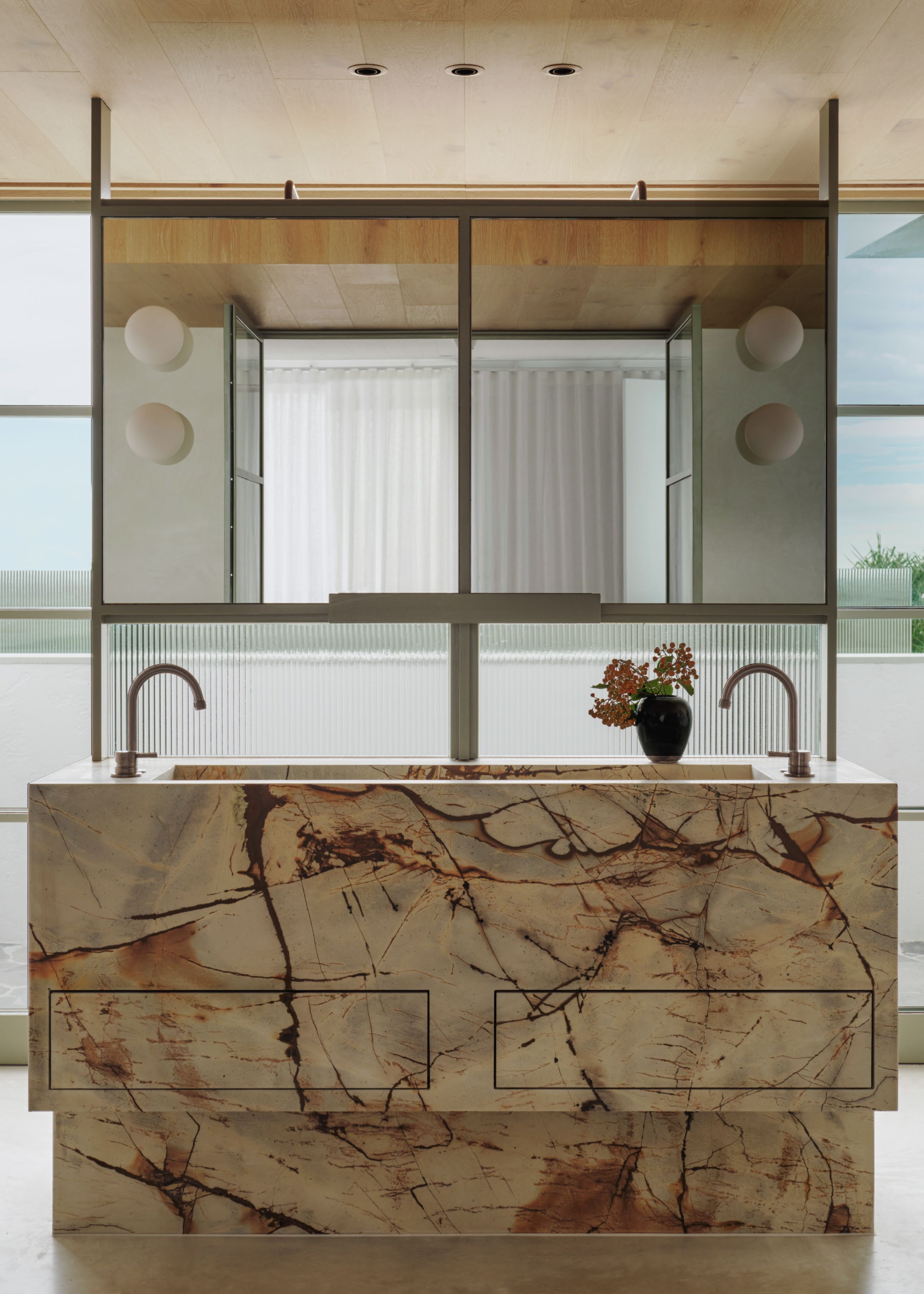 A luxurious bathroom featuring a Roma Blue Quartzite vanity with striking veining, designed with integrated drawers, complementing the earthy palette of the space.