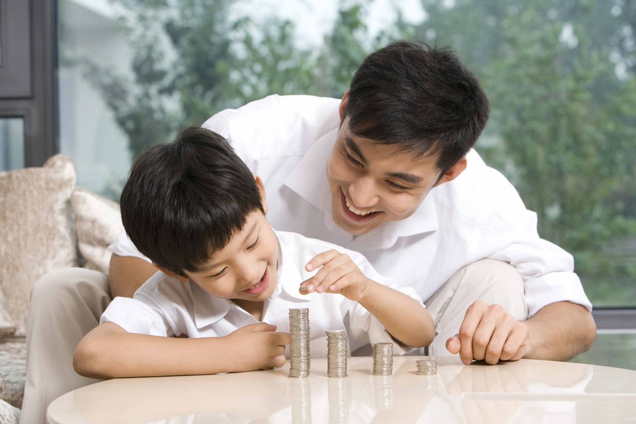 Photo of a boy and his father stacking coins