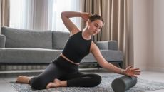 A woman performing mobility exercise at home with a foam roller