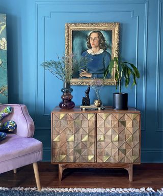 Blue bedroom walls with a purple chair and wooden dresser