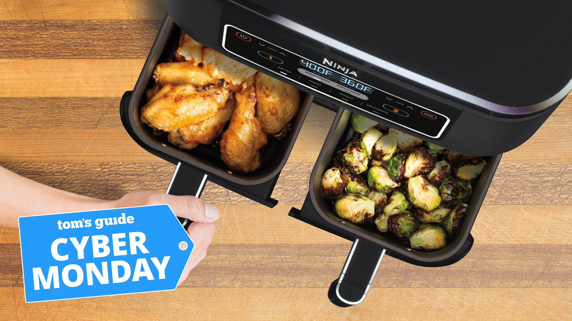 A hand pulls out the baskets from a Ninja Foodi 4-in-1 8-quart air fryer with cyber monday tag