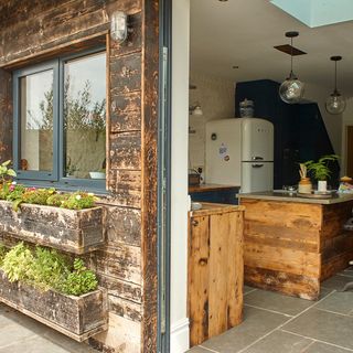 outdoor kitchen area with and fridge and wooden counter and wooden wall