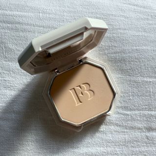 An open Fenty Beauty Pro Filt'r Soft Matte Powder Foundation in shade 120 set against a white linen background