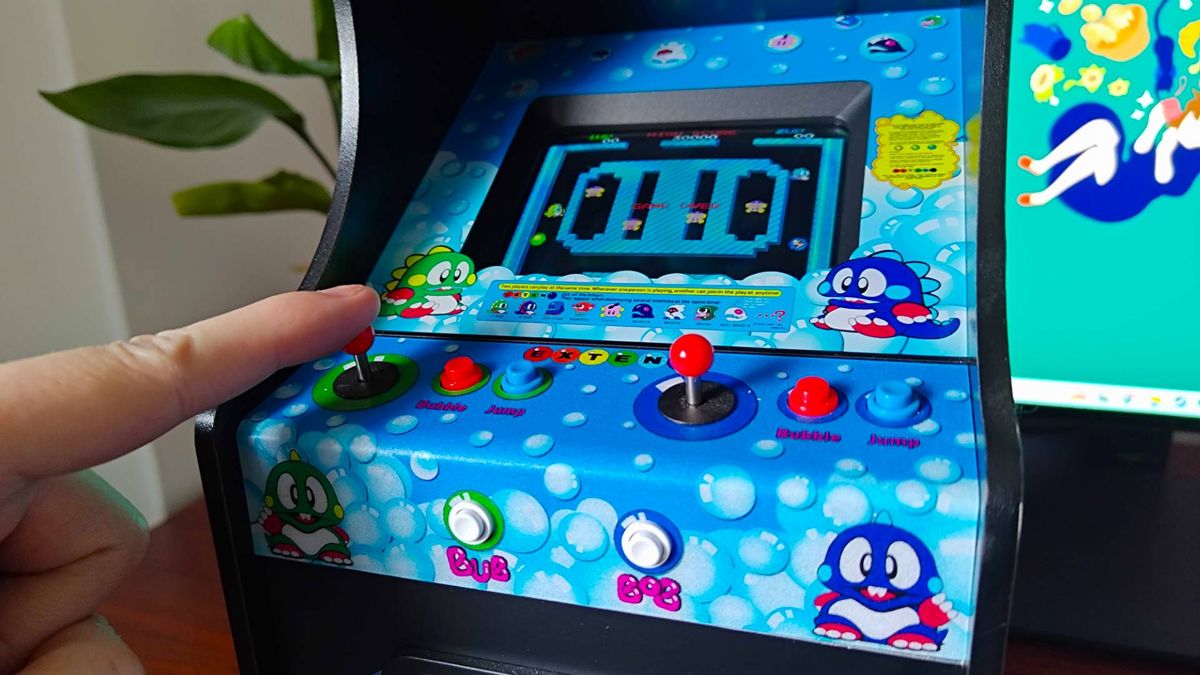 Close up of Quarter Arcades Bubble Bobble machine with finger on left joystick.