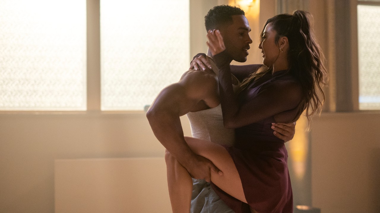 Alfie holding Mindy's leg as she puts a hand on his face while they're dancing during Emily in Paris.