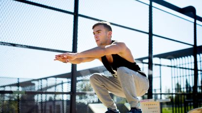 A man performing a squat jump outdoors