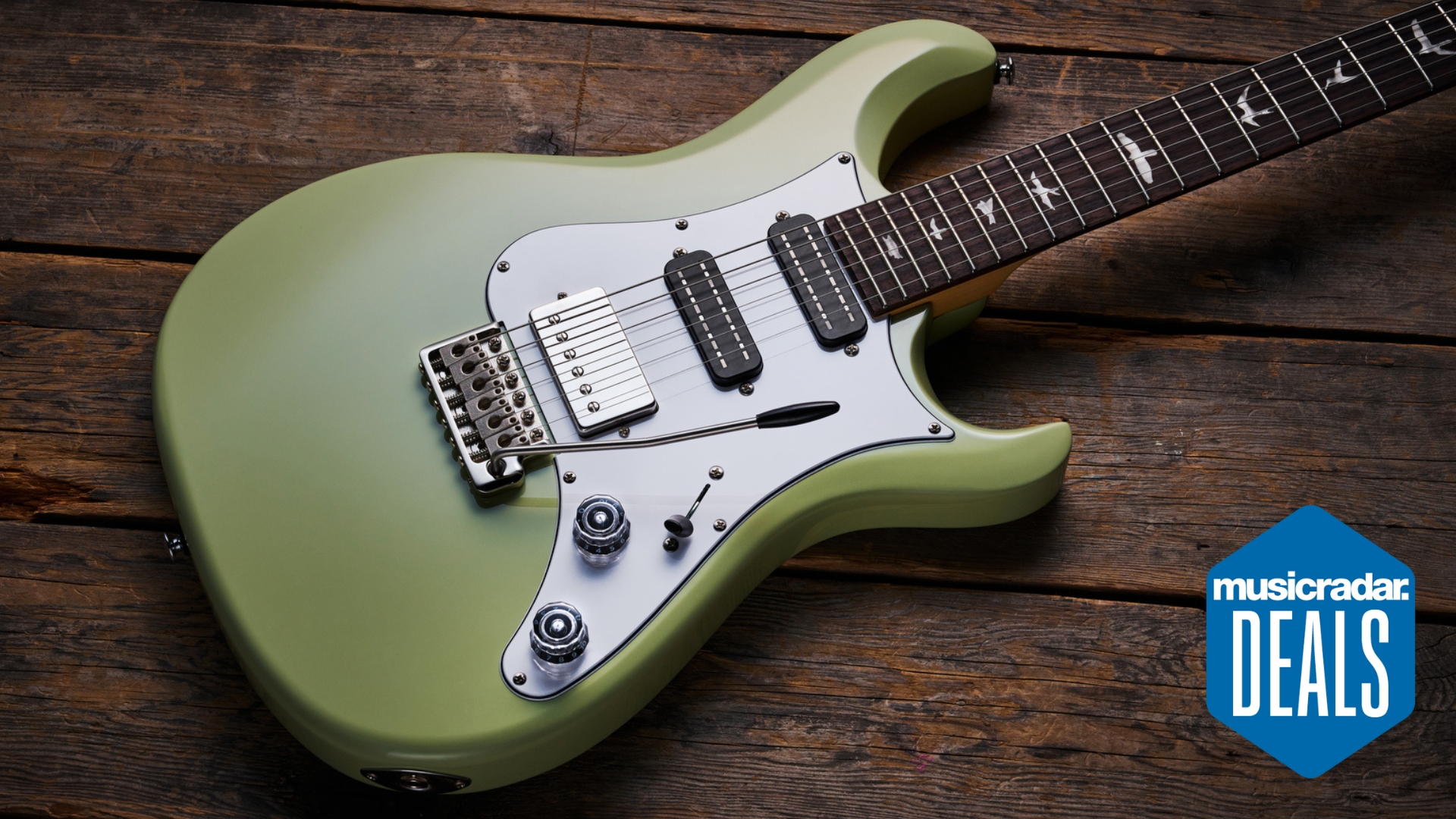 A PRS SE Studio Standard electric guitar lying on a wooden floor