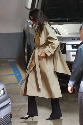 Kendall Jenner wearing a tan trench coat with black trousers and black pointed toe heels