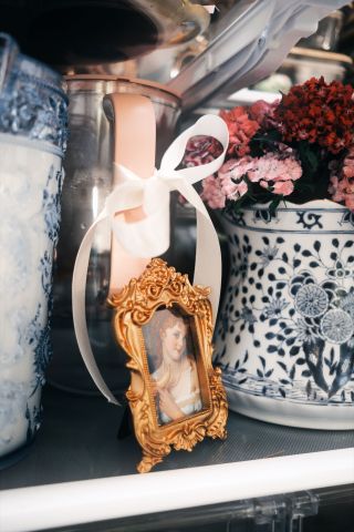 fridge shelf with gold picture frame and blue and white vases