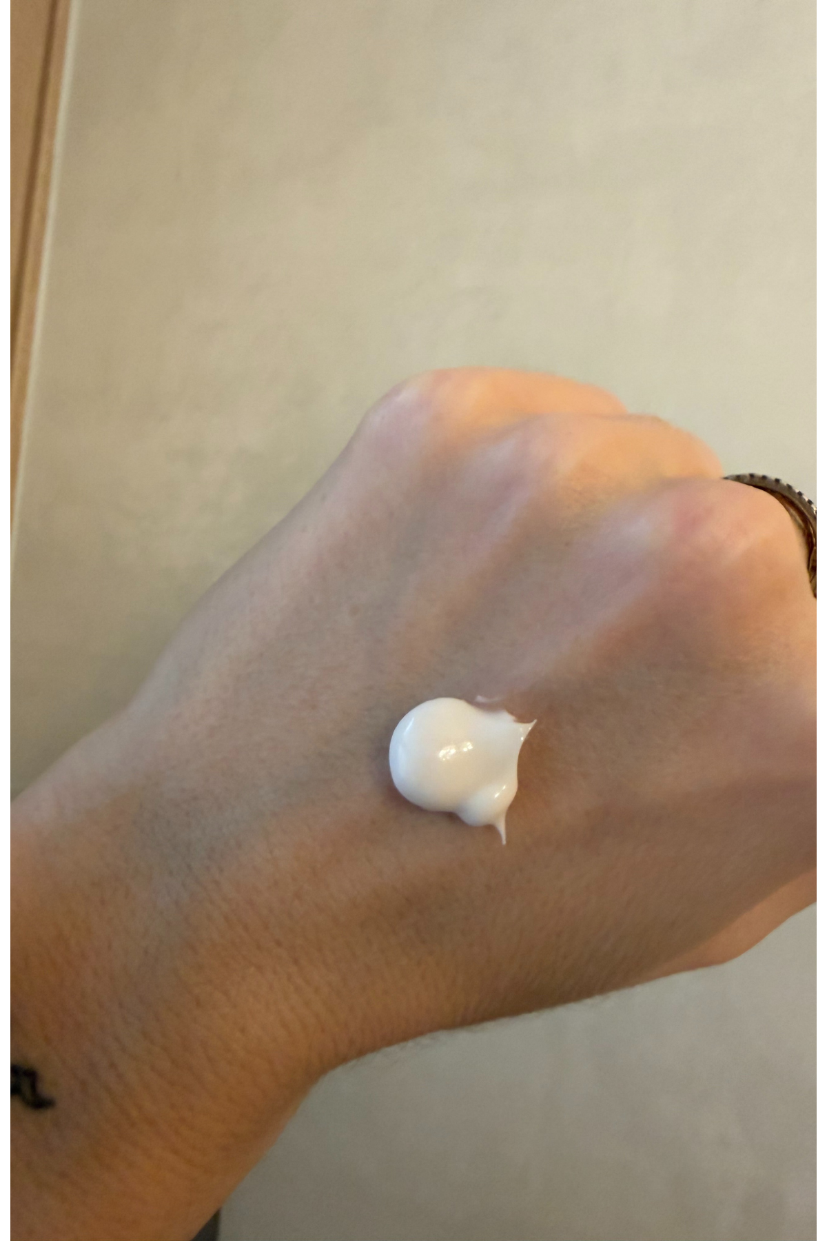 a hand with a drop of white face cream on the back