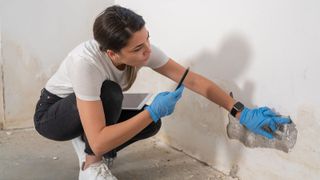 woman checking walls for damp