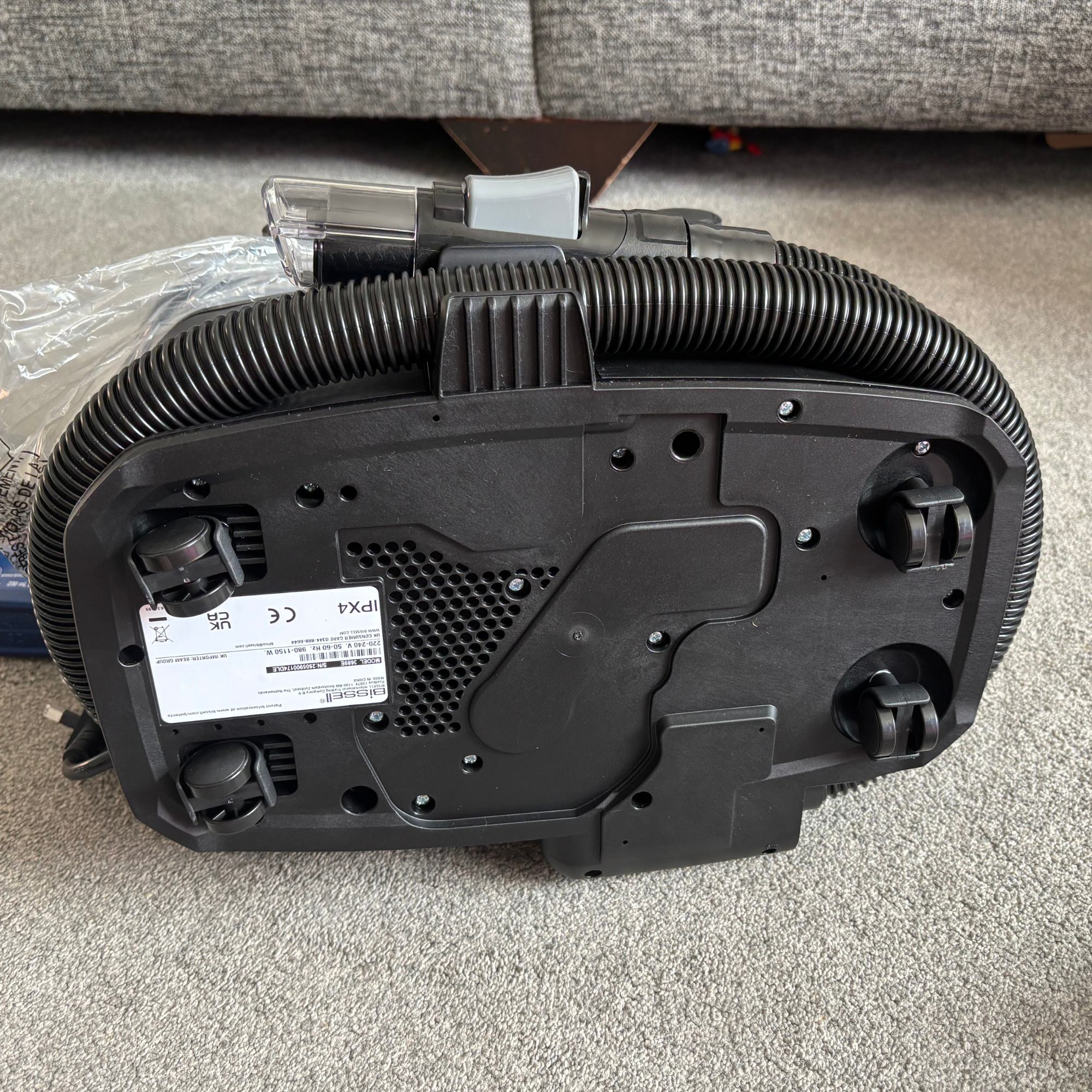 Bissell SpotClean HydroSteam laying on its side on grey carpet