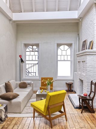living room with white brick walls, grey sofa, yellow chair and steel coffee table