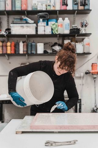 Olivia Aspinall s pouring the material from a white canister into a mold.