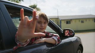 Ruby signing to her family from the car as she rides away