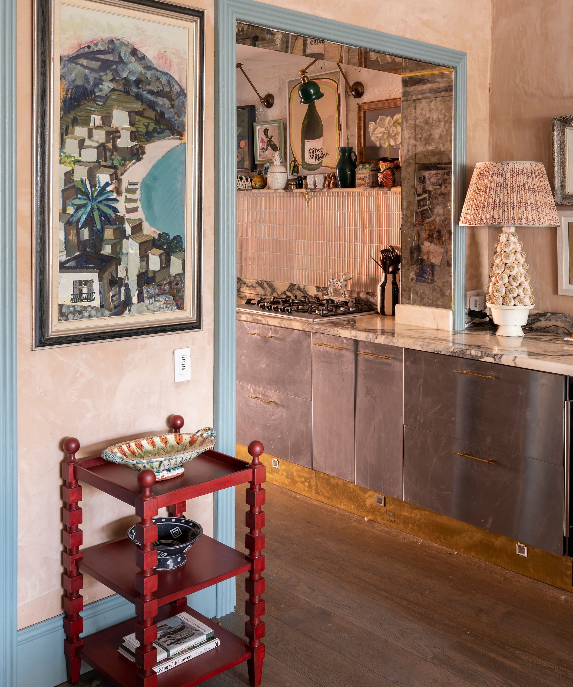 modern kitchen with plastered walls and light blue wood work with a little red side table and art on the walls