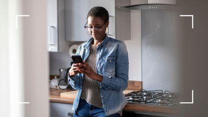 Woman standing in the kitchen on her phone, looking up how much should I weigh