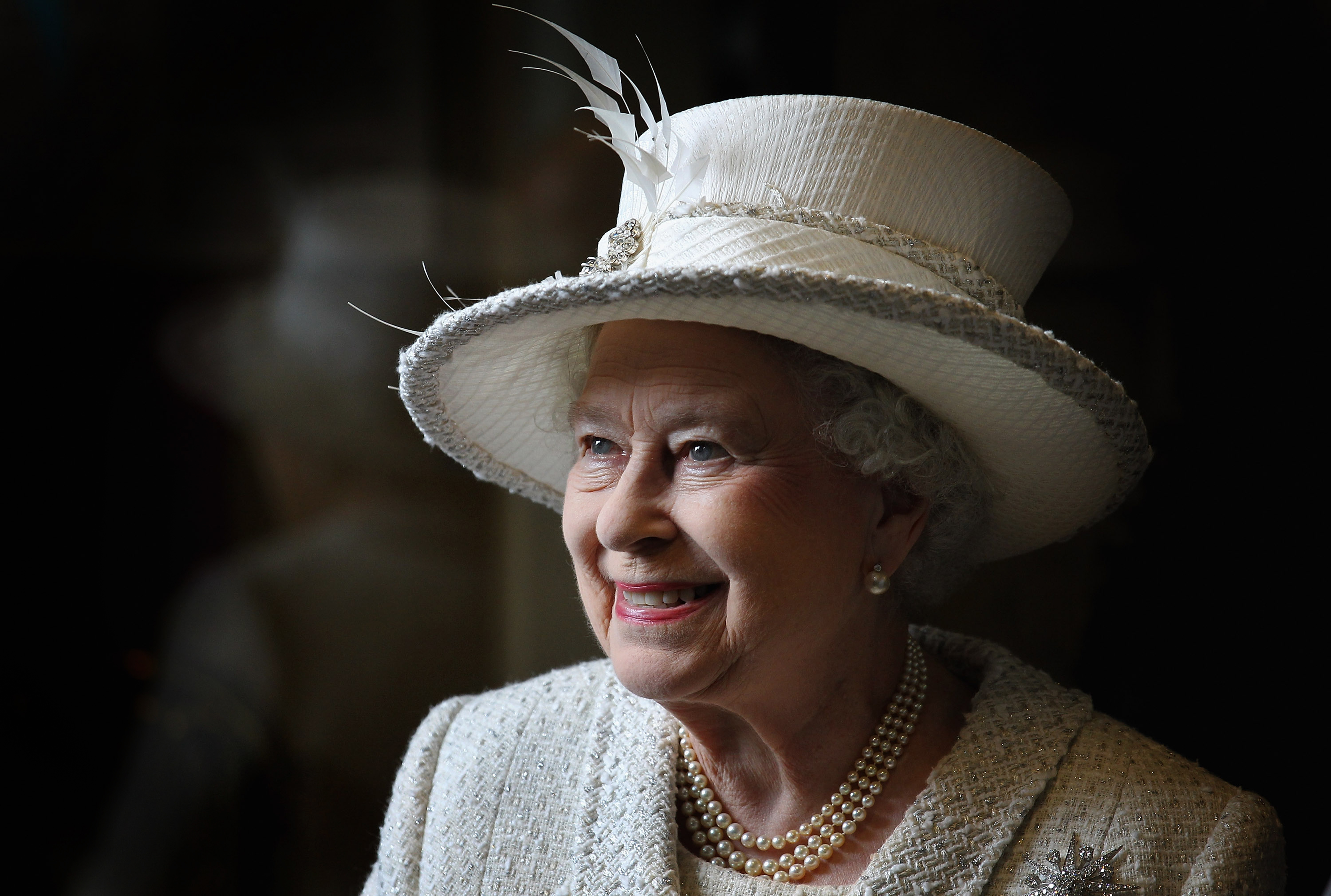 Queen Elizabeth wearing a tweed hat and coat and smiling