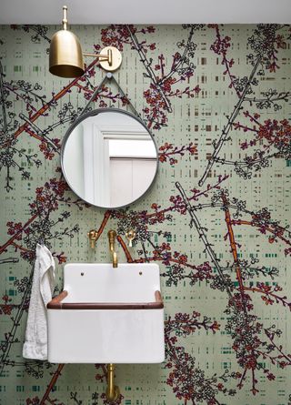 powder room with wallpaper, white basin, brass taps and pendant, round mirror
