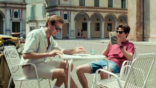 Armie Hammer and Timothee Chalamet sit at a table in Call Me by Your Name