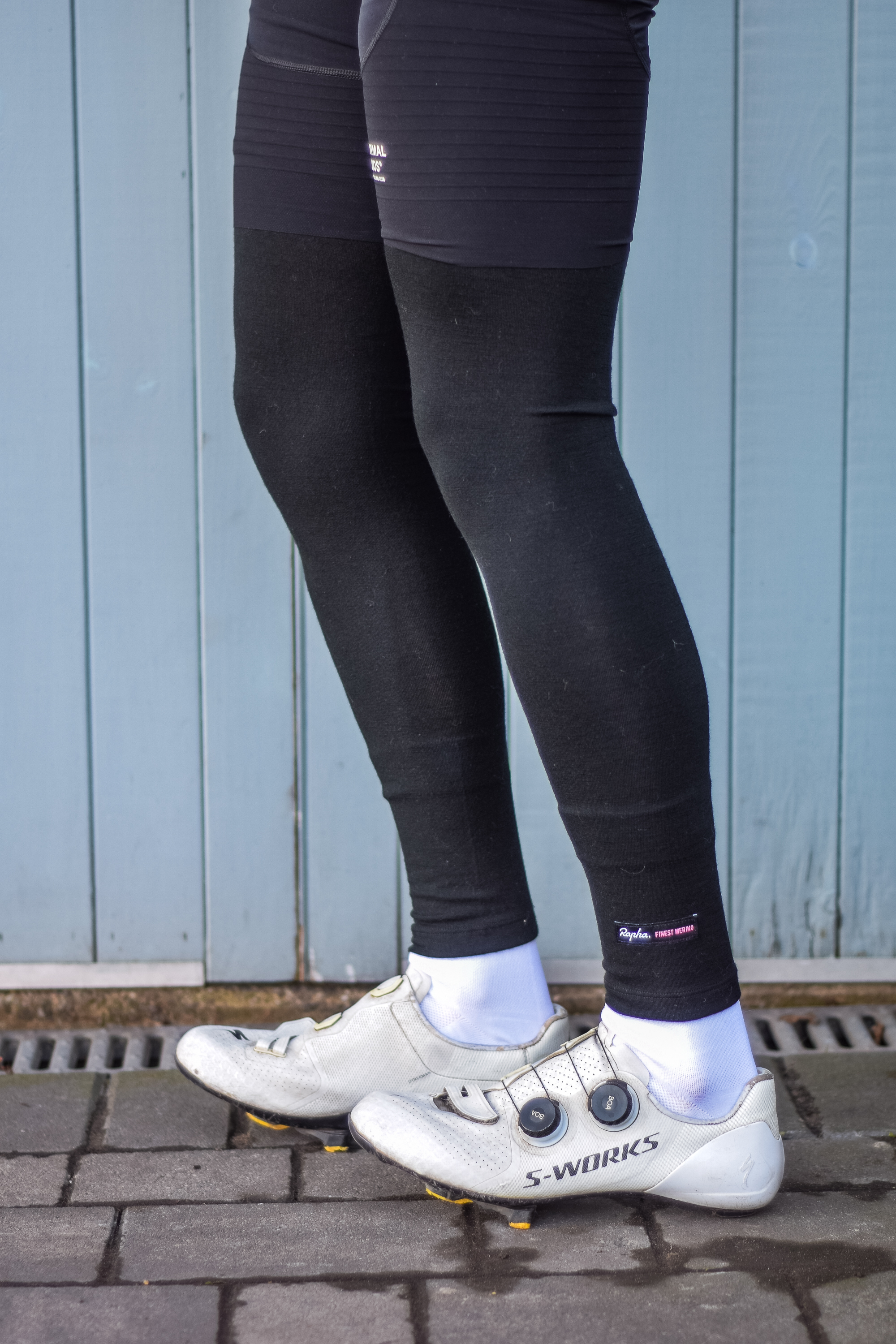 A man wearing cycling shorts and leg warmers in front of a blue door 