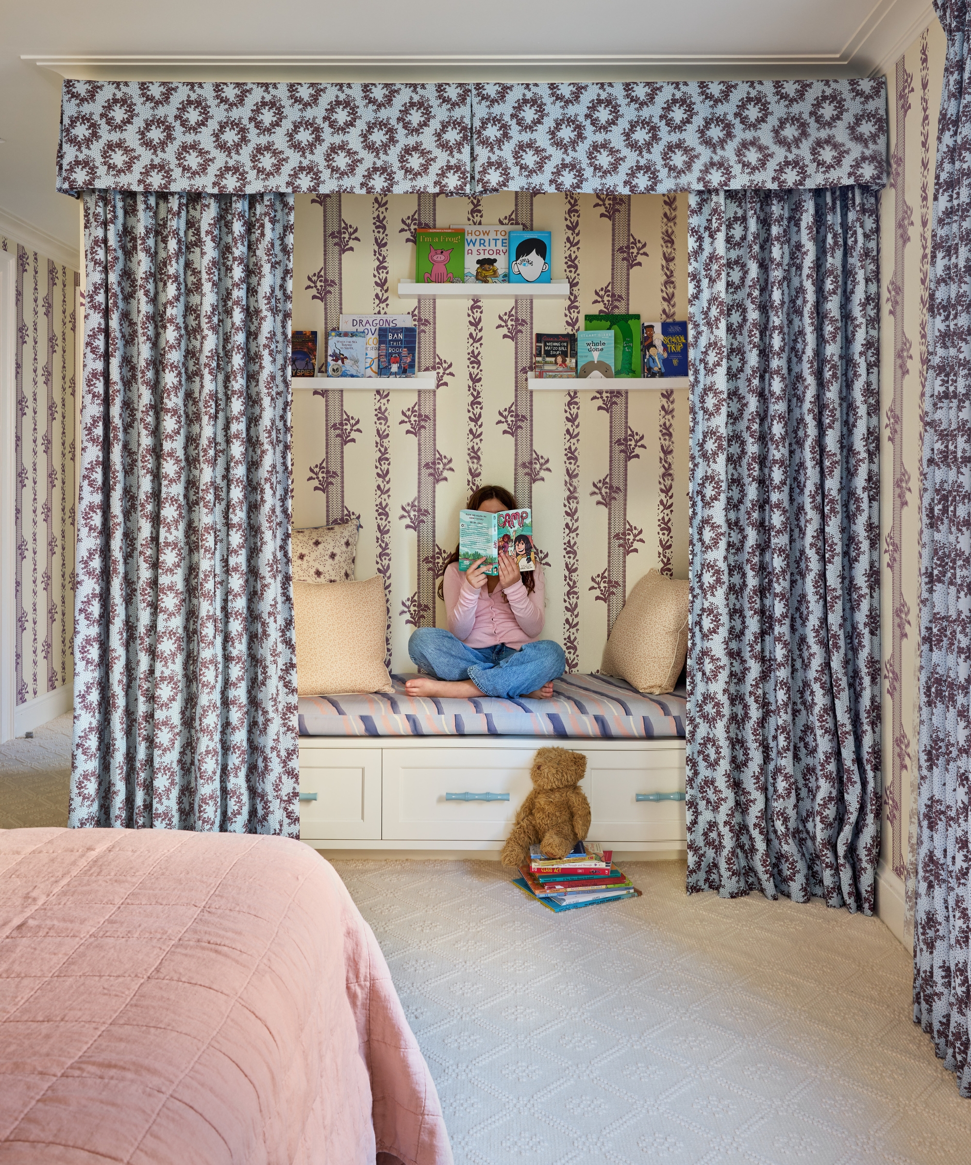 Built-in reading nook with floral curtains, book ledges, hidden storage and a child reading.