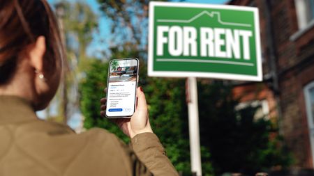 A woman looks at a rental listing on her phone.