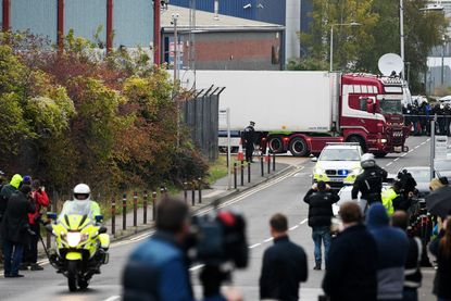People gather to watch as a lorry, in which 39 bodies were discovered in the trailer, is driven from the site to a secure location where further forensic investigation can take place, on Octo