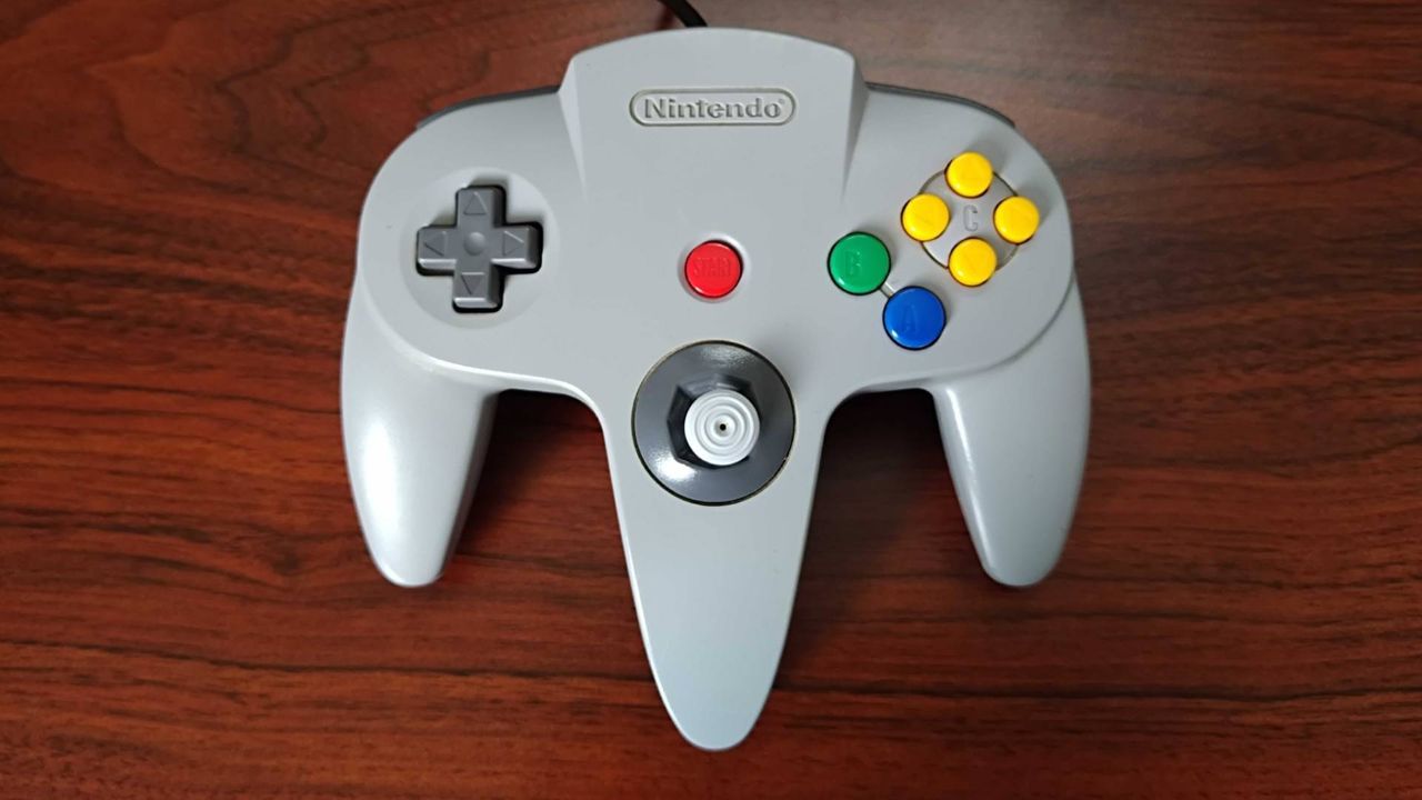 N64 controller before restoration on woodgrain desk.