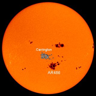 A satellite image of the orange sun, showing a sketch of the large 1859 sunspot next to a real image of a sunspot from 2003. The spots are equal in size and roughly one tenth the width of the visible sun.