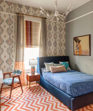 child's bedroom with ethnic wallpaper feature walls and gray walls, blue bed and orange chevron rug