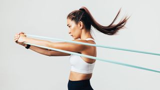 3 best resistance bands arm workouts: image shows woman using resistance band