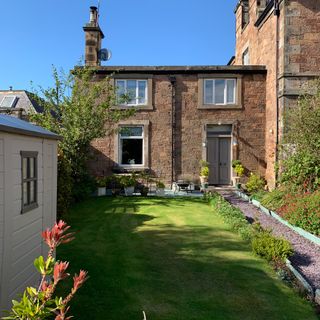 small house with garden, lawn and shed in foreground