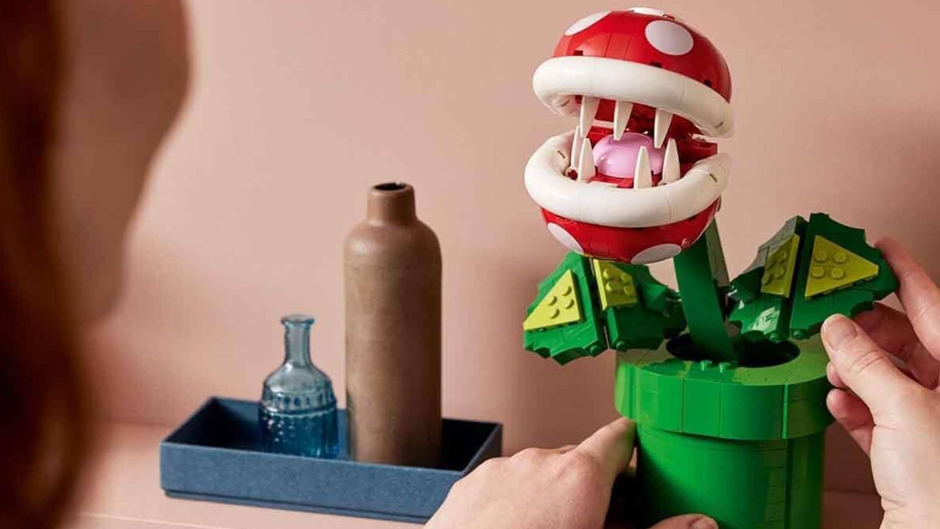 Hands move Lego Super Mario Piranha Plant on shelf