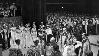 2nd June 1953: Queen Elizabeth II holds the Rod with Dove (symbolizing equity and mercy) in her left hand and the Sceptre with Cross (symbolizing royal power and justice) in her right hand, shortly after being crowned in Westminster Abbey London.