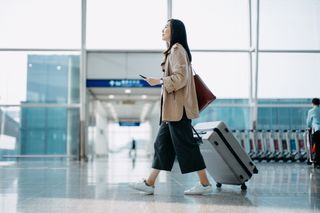 A woman walking through an airport with a suitcase