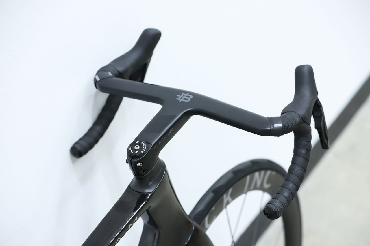 A Black Factor Ostro Vam leans against a white wall