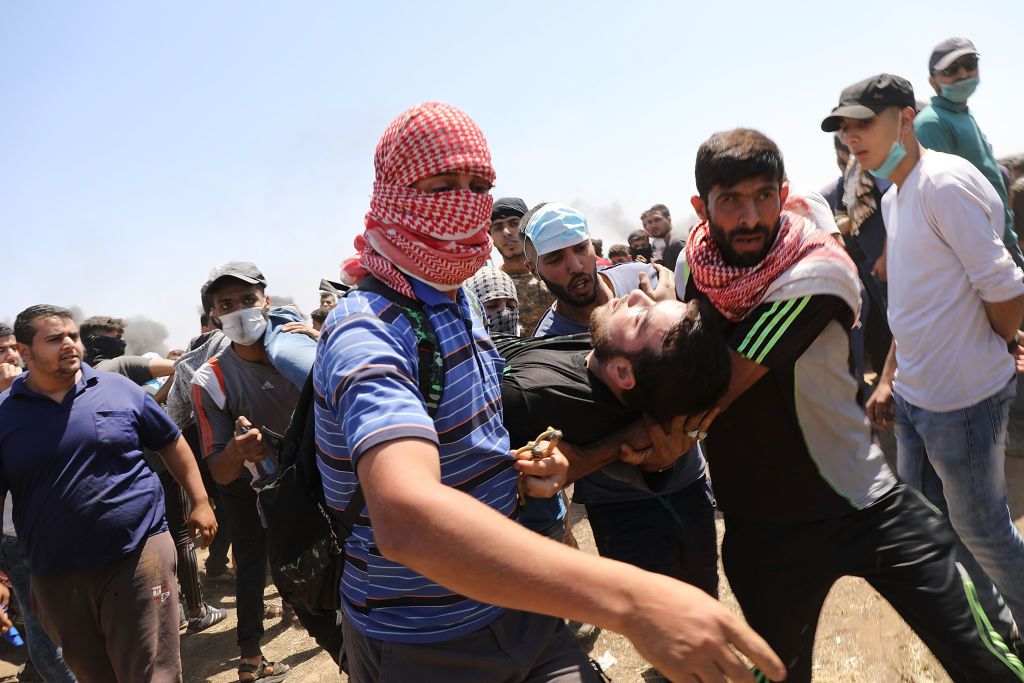 A wounded Palestinian man is rushed to an ambulance.