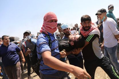 A wounded Palestinian man is rushed to an ambulance.