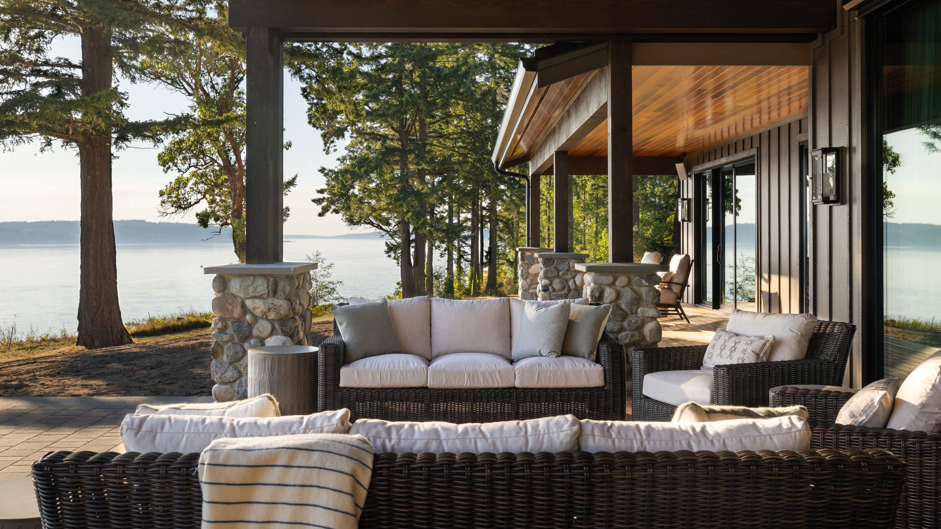 A veranda overlooking the sea on a modern home with outdoor sofas and an armchair. 
