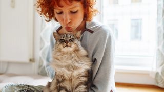 Girl kissing a cat sitting on her lap