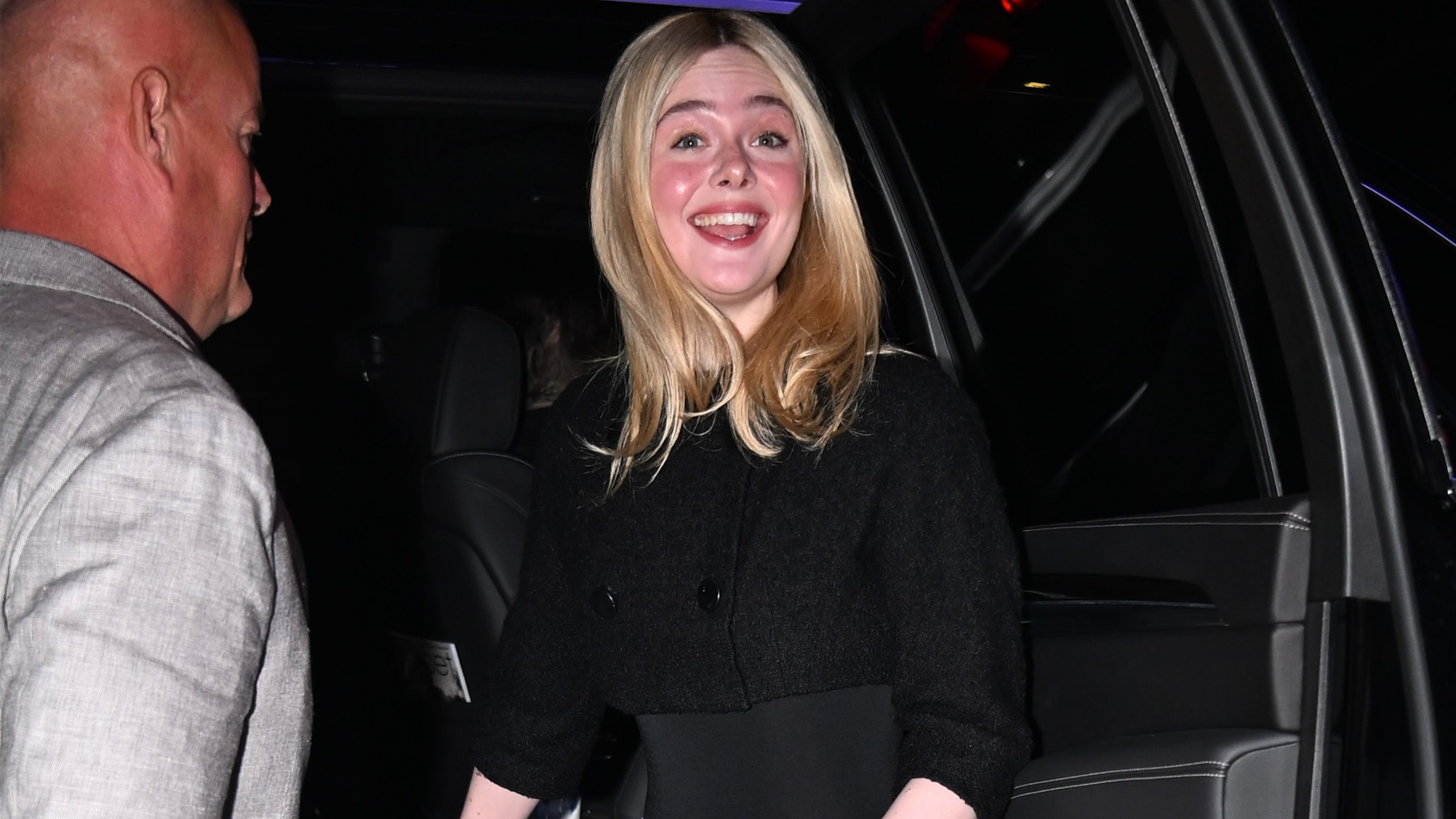 Ella fanning wears a black top with wide-leg jeans.