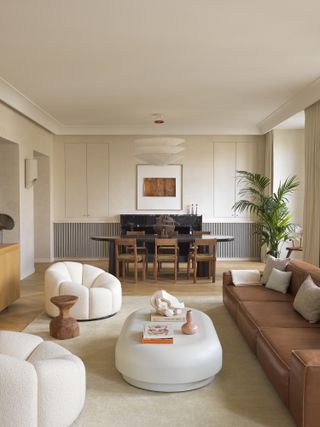 A living room with white armchairs, and a brown sofa