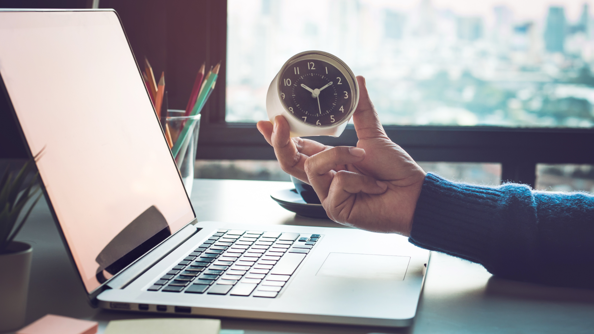 businessman holding clock by laptop