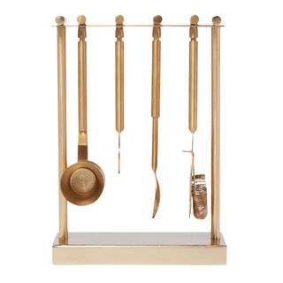 set of five gold metal cocktail making tools on a stand
