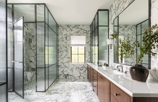 A luxury black and white bathroom with slab shower and dark wood cabinetry