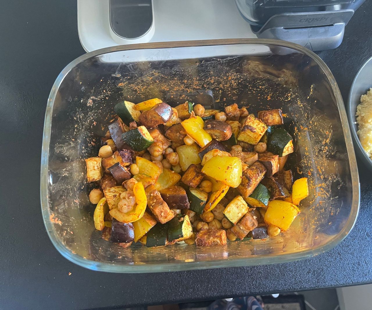 A glass air fryer basket viewed from above, with roasted vegetables inside.
