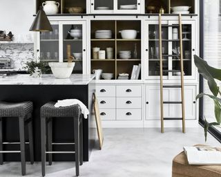 A monochrome kitchen with black island and white dresser with ladder by Neptune