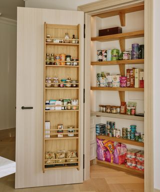 small pantry cupboard built into wall with wooden shelving inside and wooden shelving fitted to back of door