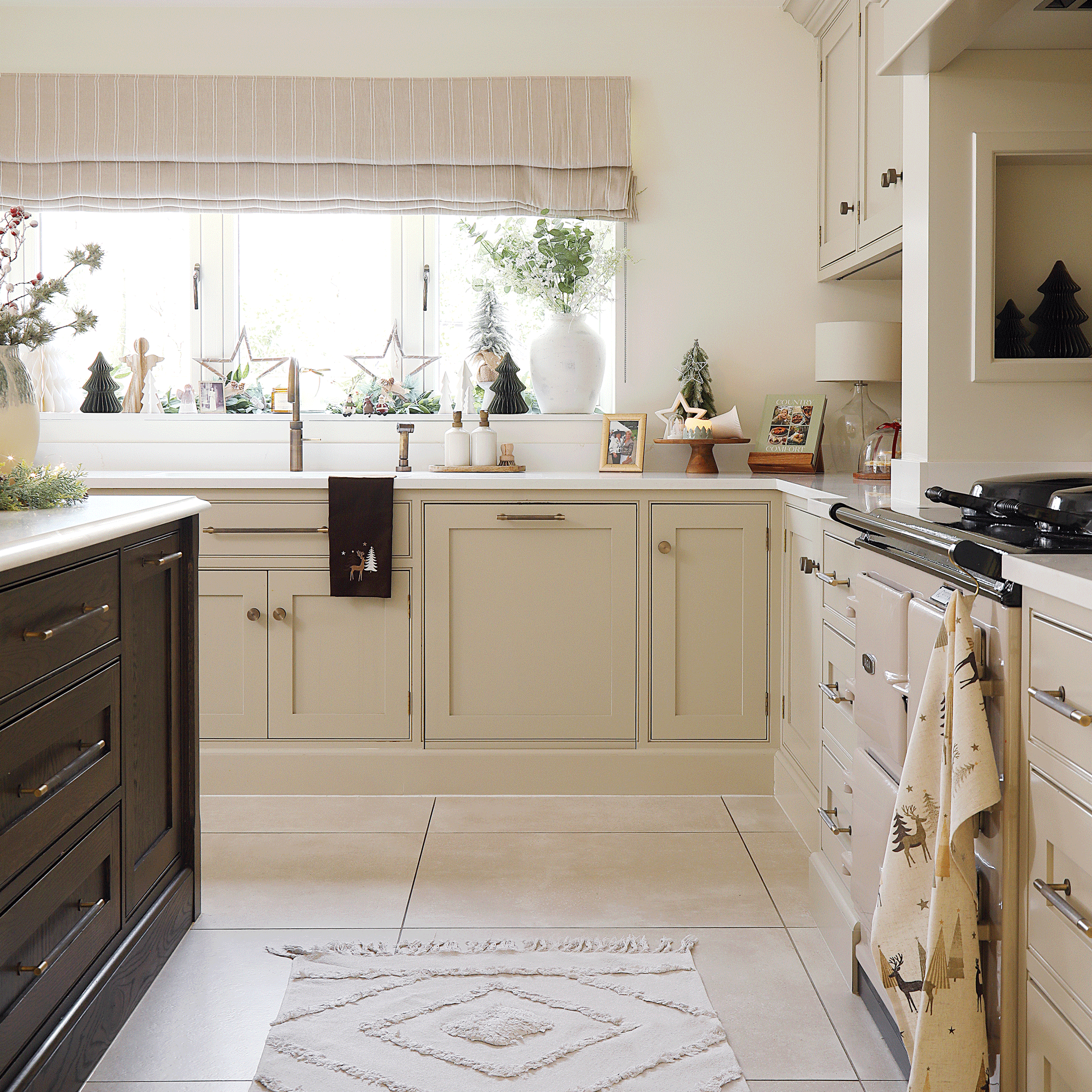 a large Shaker kitchen with neutral cabinetry a dark wood island with Christmas decor